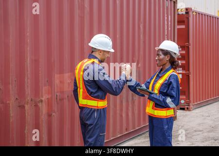 Female engineer shaking hands with male colleague at shipping yard to show teamwork in logistics. Perfect for industry, teamwork, and engineering conc Stock Photo