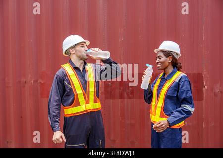 Two construction workers drinking water during break at a job site, emphasizing the importance of hydration in safety. Ideal for labor, health, and wo Stock Photo