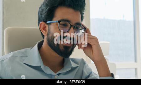Smiling Indian Arabian business man working laptop at office typing project satisfied male businessman entrepreneur ethnic CEO executive manager Stock Photo