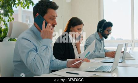 Diverse business team working laptops help customer service call center indoor office businessmen businesswoman talking mobile phone callcenter Stock Photo
