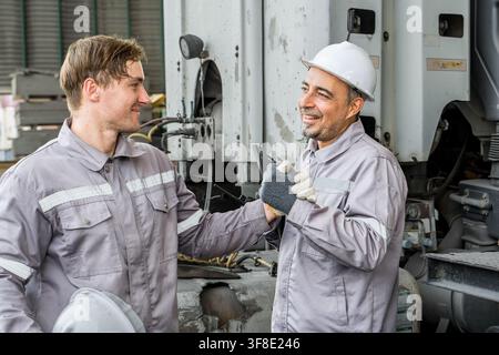 Two male construction workers shaking hands at a job site, celebrating their success. Ideal for concepts of teamwork, collaboration, and workplace rel Stock Photo
