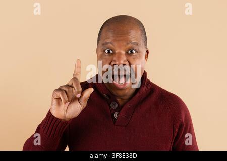 Excited mature African American man raising one finger with surprised expression Stock Photo