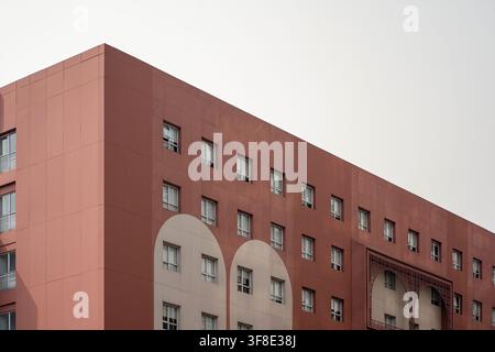 Red modern architecture building exterior with white arches and corner view. Stock Photo