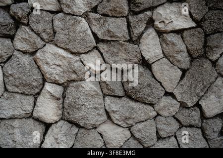 Stone wall texture of rough irregular stacked rocks for background. Stock Photo