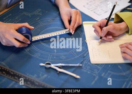 Engineer measures detail on blueprint as colleague marks notes Stock Photo