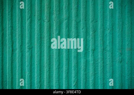 Green corrugated wall texture with vertical ridges and rough painted surface. Stock Photo