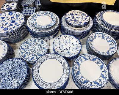 Decorative ceramic plates with intricate blue floral patterns stacked on a marble surface in a retail display setting Stock Photo