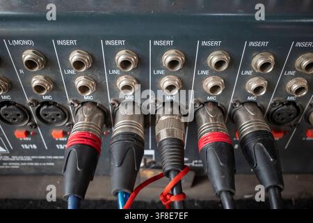 Detailed close-up view of multiple XLR connectors and audio cables plugged into the input panel of an analog audio mixer console. Perfect concept for Stock Photo