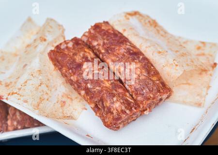 Raw traditional Romanian skinless minced meat rolls known as mici placed on parchment paper ready for grilling, Romania. Stock Photo