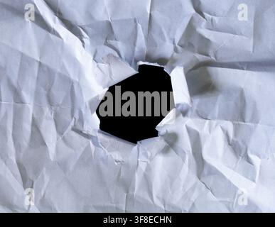 Torn Hole in Crumpled White Paper with Black Empty Space in Center Stock Photo