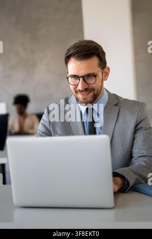 Business man at a desk working on his laptop, focused on his digital workspace in an office setting Stock Photo