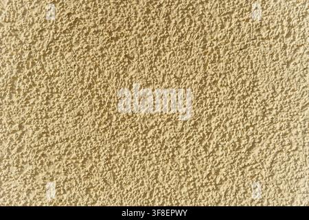 Rough textured yellow stucco wall surface, showing detailed plaster finish for construction or architecture backgrounds, texture Stock Photo
