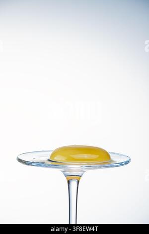 Whole egg yolk resting on a glass coupe stand with warm lighting, food photography Stock Photo