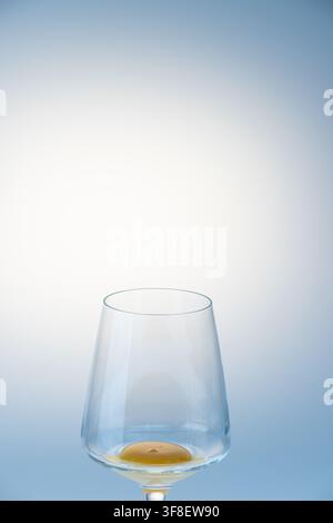 Empty wine glass standing upright with a small trace of egg yolk residue at the base Stock Photo