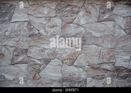Stone wall texture with irregular brown and gray slate tiles pattern. Stock Photo