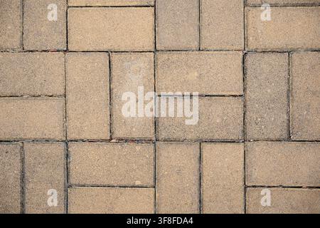Paving stone texture with yellow rectangular interlocking bricks in a herringbone pattern Stock Photo