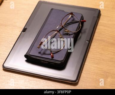 Metal Framed Eyeglasses Resting on Digital Tablet Computer Case Stock Photo