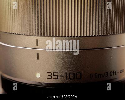 Macro close up of a camera telephoto zoom lens barrel showing the focus ring texture and focal length indicator markings Stock Photo