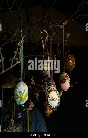 Decorative hand painted Easter eggs hanging from branches in a traditional market display celebrating spring and holiday traditions Stock Photo