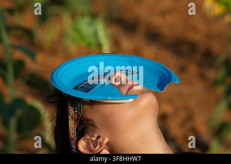 Sahagun, Leon, Spain. 12th Aug, 2026. A girl wearing eclipse glasses looks at the sky, during a total solar eclipse in a sunflower field in the town of Sahagun, Castile and Leon, Spain. (Credit Image: © Luis Soto/ZUMA Press Wire) EDITORIAL USAGE ONLY! Not for Commercial USAGE! Stock Photo
