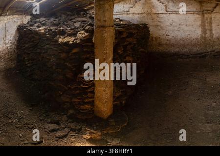 Interior of Rustic barn with stack of dried dung bricks arranged in a rectangular pile, traditionally used as fuel. Stock Photo