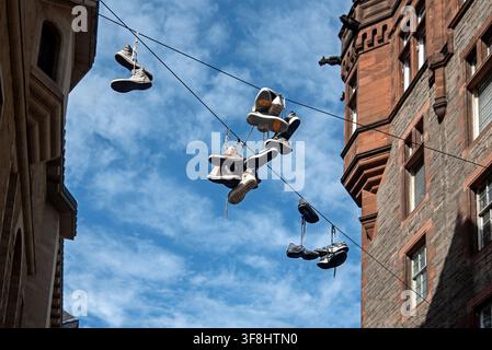 Pairs of shoes hanging by their laces from a wire straddling the Cowgate in Edinburgh's Old Town. Stock Photo