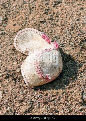 Worn Baseball Cover Lying on Dirt Warning Track at Baseball Field Stock Photo