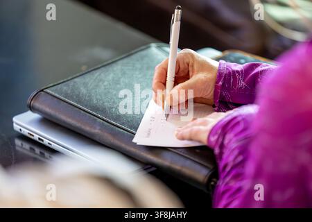A woman's hand jots down written notes with a pen onto a notepad Stock Photo