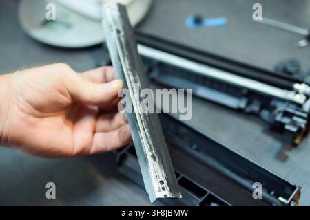 Refilling a laser printer toner cartridge with black powder, close-up view of hands and tools. The image shows the process of opening the cartridge, p Stock Photo