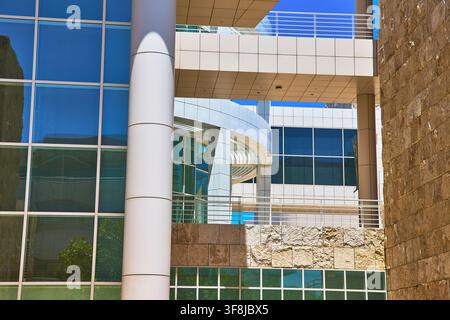 The Getty Center in Los Angeles California features modern glass architecture framed by stone walls and sleek columns under a vibrant blue sky. Sunlig Stock Photo