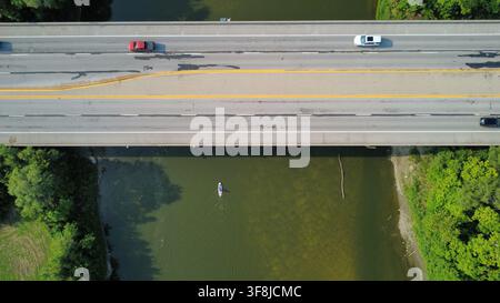 Aerial drone view of vehicles crossing a bridge over a river in summer. Stock Photo