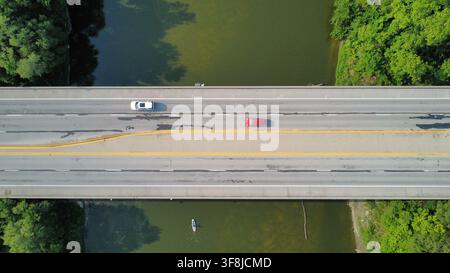 Aerial drone view of vehicles crossing a bridge over a river in summer. Stock Photo