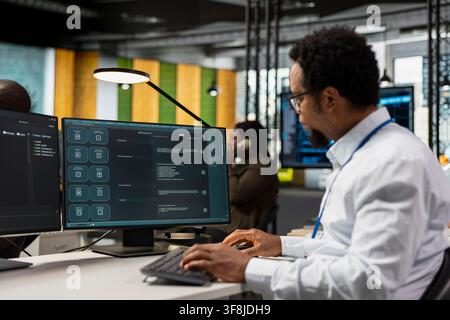 IT worker in AI tech company workplace using LLM chatbot to conduct code reviews. Developer using large language model program at office desk to design and implement machine learning algorithms Stock Photo