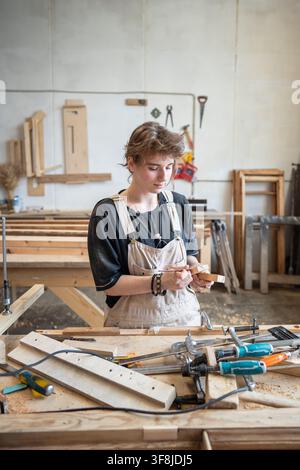 Process of restoration in woodworking studio, woman carpenter measures blocks for patch with ruler Stock Photo