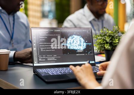 Close up of AI startup engineers brainstorming to create deep learning models with laptop. IT workers use notebook, collaborating on artificial intelligence project to develop solutions for businesses Stock Photo