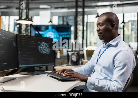System administrator in office automating repetitive tasks using AI scripts on PC. IT specialist uses artificial intelligence tech on computer to speed up feature implementation Stock Photo