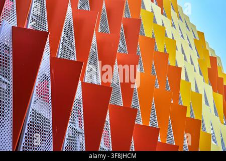 Modern Geometric Facade With Red Orange Yellow Triangular Panels And Perforated Metal Stock Photo
