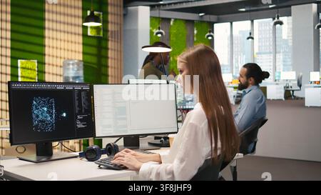 Startup office IT professional using AI LLM chatbot, optimizing systems performance. Computer scientist uses artificial intelligence assistant to automate workflows, camera A Stock Photo