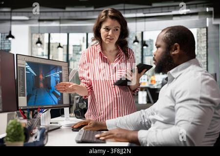 Game developers working on futuristic video game on computer, diverse team uses programming tools and software to design virtual world with spaceships and stations. Assets for gaming industry. Stock Photo