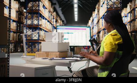 Female warehouse clerk registering barcodes for packages, scanning the shipping labels and awb tags on cardboard boxes. Fulfillment center distribution operations for e-commerce. Camera A. Stock Photo