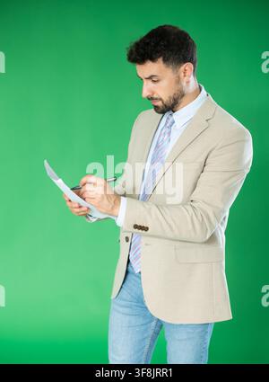 Adult man making notes on paper documents in front of green screen Stock Photo