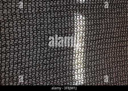 A close-up view shows a black mesh pattern with soft blurred light behind it. Stock Photo