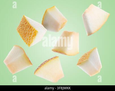 Sweet melon pieces flying in air on pastel green background Stock Photo
