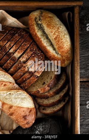 Bread Still Life. An assortment of different breads in a wooden box on a rustic wood table. Stock Photo