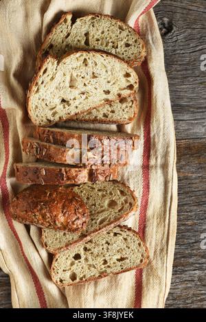 Artisan Bread Still Life. A fresh baked and sliced loaf of multi grain bread on a kitchen towel. Stock Photo
