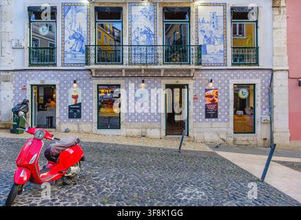 Red Vespa scooter parked in street in front of Pastelaria Santo Antonio, decorated with vintage Portuguese tiles, Lisbon, Portugal Stock Photo