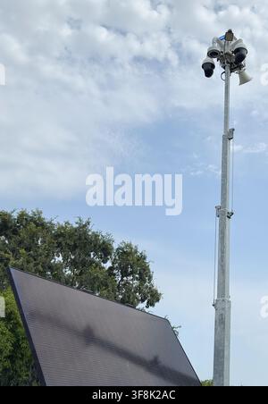 Solar powered mobile security camera trailer with dome cameras, megaphones, solar panels operating in commercial parking lot for crime deterrence Stock Photo