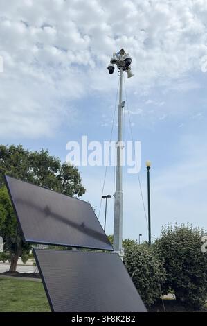 Solar powered mobile security camera trailer with dome cameras, megaphones, solar panels operating in commercial parking lot for crime deterrence Stock Photo