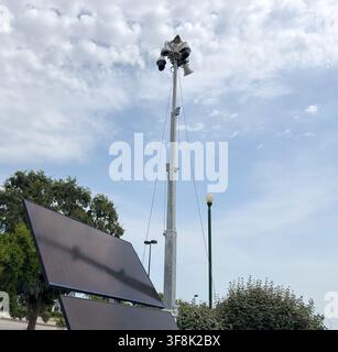 Solar powered mobile security camera trailer with dome cameras, megaphones, solar panels operating in commercial parking lot for crime deterrence Stock Photo