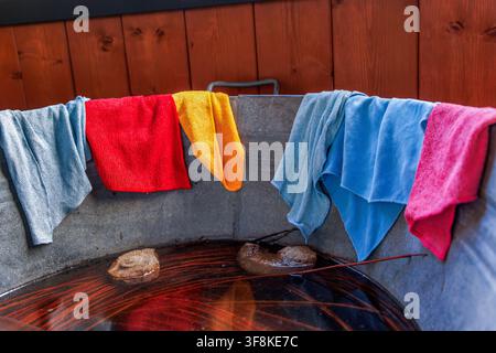 Colorful reusable microfiber cleaning cloths and towels draped over the rim of a galvanized metal tub Stock Photo